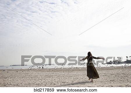 Stock Photo - Woman in dress playing on beach. Fotosearch