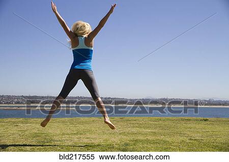 Stock Photography - Woman jumping for joy in field. Fotosearch