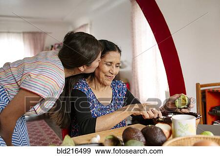 Woman kissing grandmother cooking in kitchen View Large Photo Image Stock Photo - Woman kissing grandmother cooking in kitchen. Fotosearch