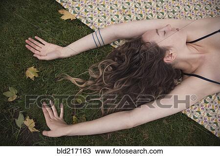Woman laying on blanket in grass View Large Photo Image Stock Image - Woman laying on blanket in grass. Fotosearch