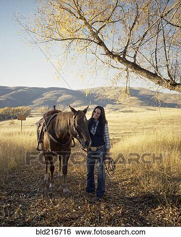Stock Photograph - Woman leading horse on dirt path. Fotosearch