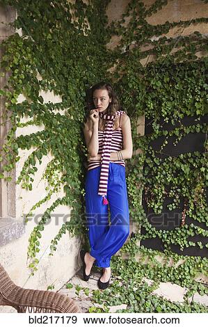 Stock Photo - Woman leaning on ivy wall. Fotosearch