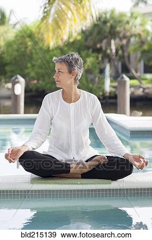 Woman meditating by still swimming pool View Large Photo Image Stock Photo - Woman meditating by still swimming pool. Fotosearch