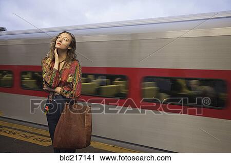 Woman missing passing train in train station View Large Photo Image Stock Image - Woman missing passing train in train station. Fotosearch