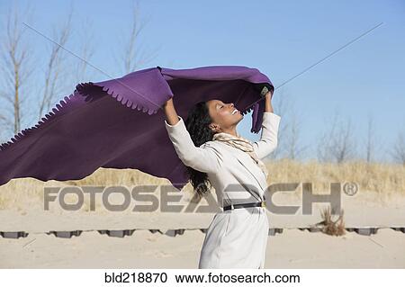 Stock Image - Woman playing with fabric on beach. Fotosearch