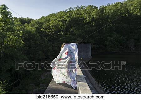 Stock Image - Woman playing with fabric on stone bridge. Fotosearch