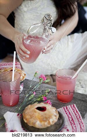Woman pouring pink lemonade into glasses on wooden table View Large Photo Image Stock Image - Woman pouring pink lemonade into glasses on wooden table. Fotosearch