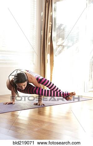 Stock Image - Woman practicing yoga in studio. Fotosearch
