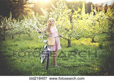 Stock Photo - Woman pushing bicycle in rural field. Fotosearch