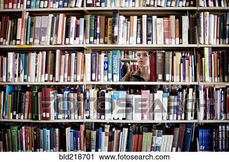 Stock Image - Woman searching for book in library. Fotosearch