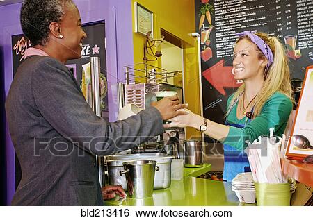 Stock Photograph - Woman serving customer smoothie in cafe. Fotosearch
