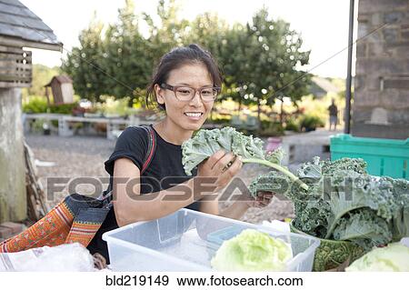 Woman shopping for greens at farmers market View Large Photo Image Stock Photo - Woman shopping for greens at farmers market. Fotosearch
