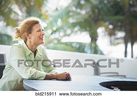 Stock Image - Woman sitting at patio bar. Fotosearch