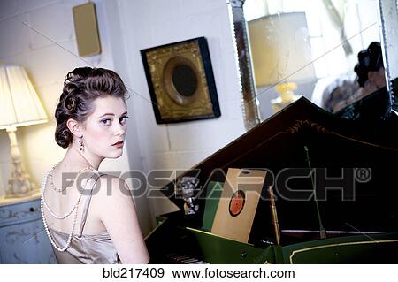 Stock Photo - Woman sitting at piano in ornate living room. Fotosearch