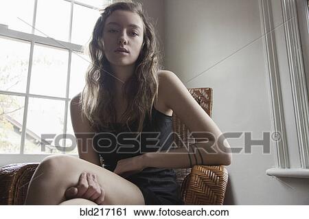 Stock Image - Woman sitting in armchair near window. Fotosearch