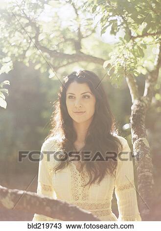 Stock Image - Woman sitting in tree. Fotosearch