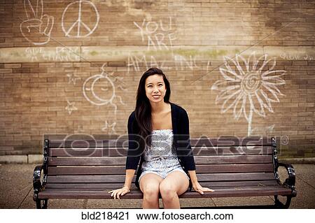 Woman sitting on urban bench near graffiti wall View Large Photo Image Stock Image - Woman sitting on urban bench near graffiti wall. Fotosearch