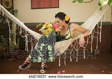 Stock Photo - Woman smelling bouquet of flowers in hammock. Fotosearch