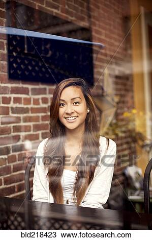 Stock Image - Woman smiling behind window in cafe. Fotosearch