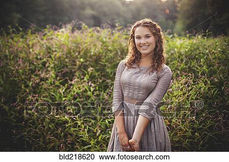Stock Image - Woman smiling in rural field. Fotosearch