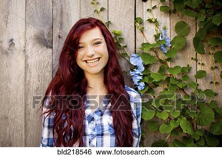 Stock Photograph - Woman smiling near wooden fence and ivy. Fotosearch