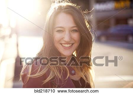 Stock Image - Woman smiling on sunny city sidewalk. Fotosearch