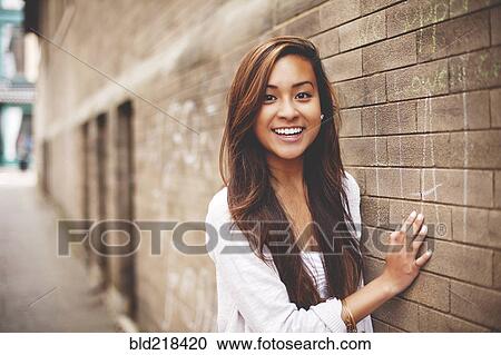 Woman standing at brick wall in city View Large Photo Image Stock Image - Woman standing at brick wall in city. Fotosearch