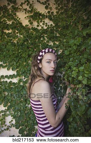Stock Image - Woman standing at ivy wall. Fotosearch