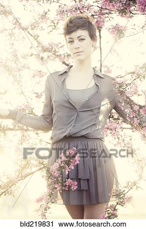 Stock Image - Woman standing in flowering trees. Fotosearch