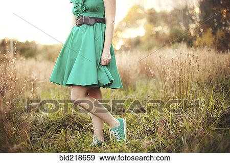 Stock Photo - Woman standing in tall grass in rural field. Fotosearch