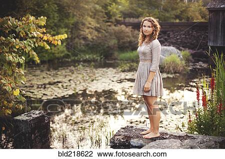 Woman standing on rock overlooking rural pond View Large Photo Image Stock Image - Woman standing on rock overlooking rural pond. Fotosearch