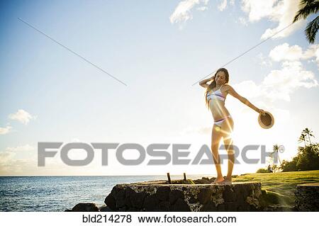 Stock Photo - Woman standing on wall near ocean. Fotosearch