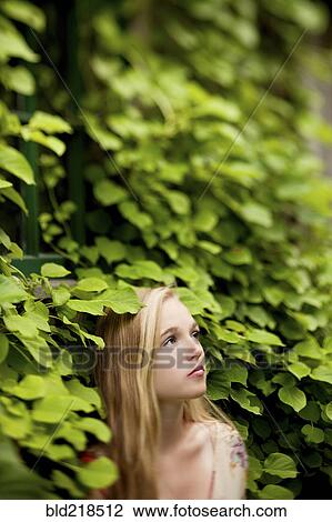 Stock Image - Woman standing under ivy wall. Fotosearch