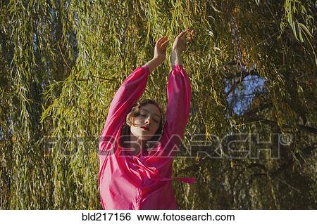 Stock Photograph - Woman standing under tree in park. Fotosearch