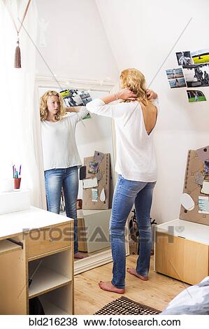 Stock Photo - Woman styling her hair in mirror. Fotosearch