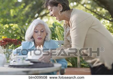 Stock Photo - Woman surprising friend with birthday cake. Fotosearch