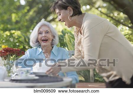 Stock Photo - Woman surprising friend with birthday cake. Fotosearch