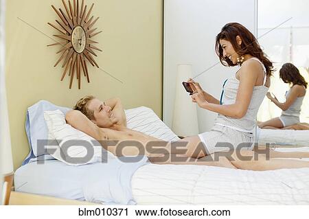 Woman taking picture of boyfriend in bed View Large Photo Image Stock Image - Woman taking picture of boyfriend in bed. Fotosearch