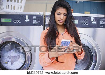 Woman using cell phone at laundromat View Large Photo Image Stock Image - Woman using cell phone at laundromat. Fotosearch