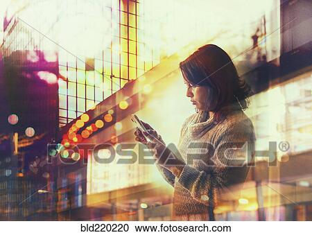 Woman using cell phone in city at night View Large Photo Image Stock Image - Woman using cell phone in city at night. Fotosearch