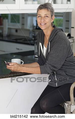 Woman using cell phone in kitchen View Large Photo Image Stock Image - Woman using cell phone in kitchen. Fotosearch
