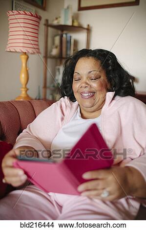 Woman using digital tablet in living room View Large Photo Image Picture - Woman using digital tablet in living room. Fotosearch
