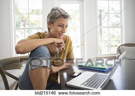 Stock Photograph - Woman using laptop in living room. Fotosearch