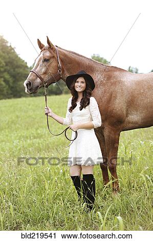 Stock Image - Woman walking horse in rural field. Fotosearch
