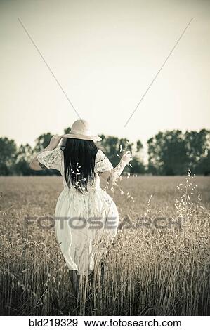 Woman walking in tall grass in rural field View Large Photo Image Stock Photo - Woman walking in tall grass in rural field. Fotosearch