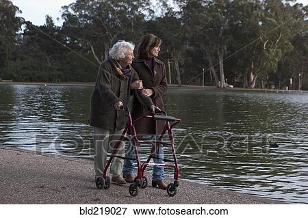 Stock Photo - Woman walking with mother at pond. Fotosearch