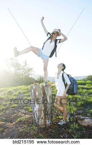Stock Photography - Woman watching friend balancing on dilapidated stump. Fotosearch