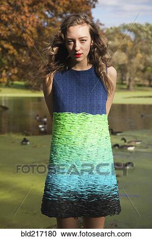 Stock Image - Woman wearing colorful dress near duck pond. Fotosearch