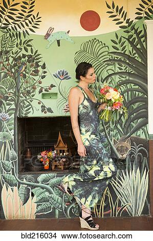Picture - Woman wearing dress matching wallpaper. Fotosearch
