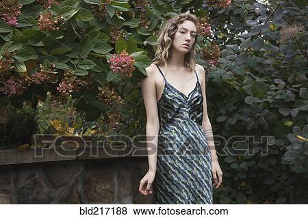 Stock Photo - Woman wearing gown in garden. Fotosearch